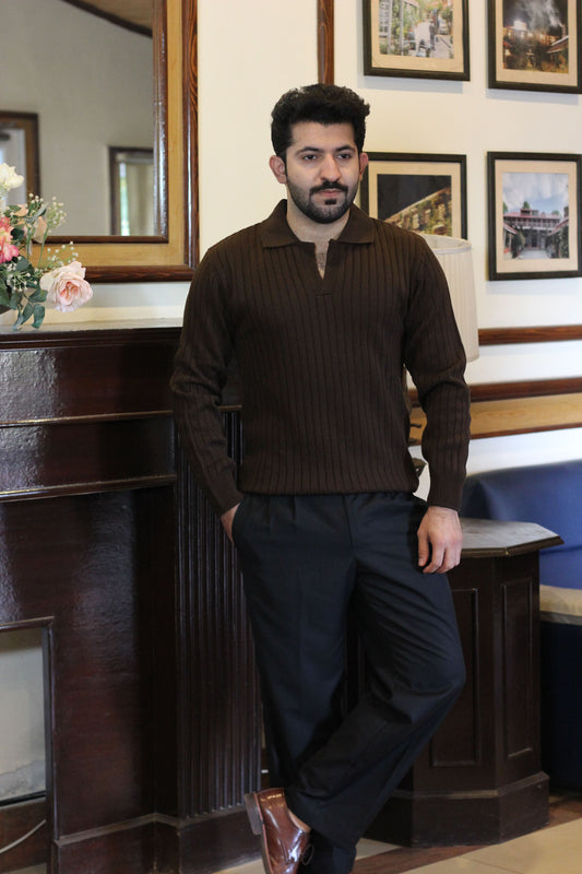 Person wearing a Brown Rib knitted Polo Sweater and black pants standing indoors with a Vintage background showing full outfit